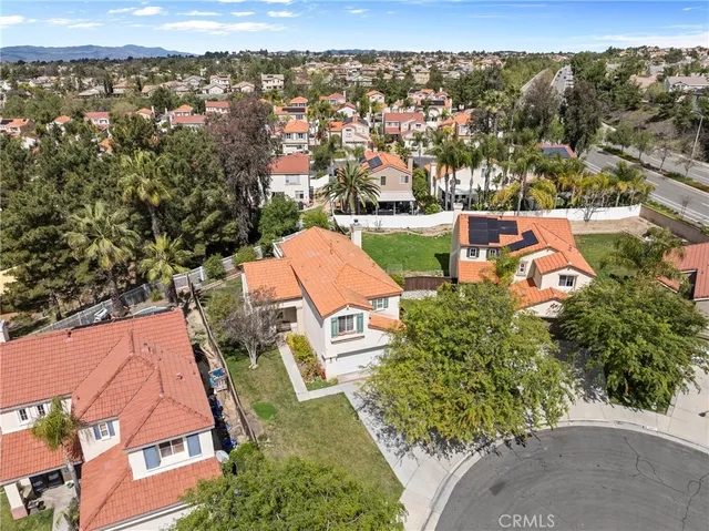 an aerial view of residential houses with outdoor space and trees