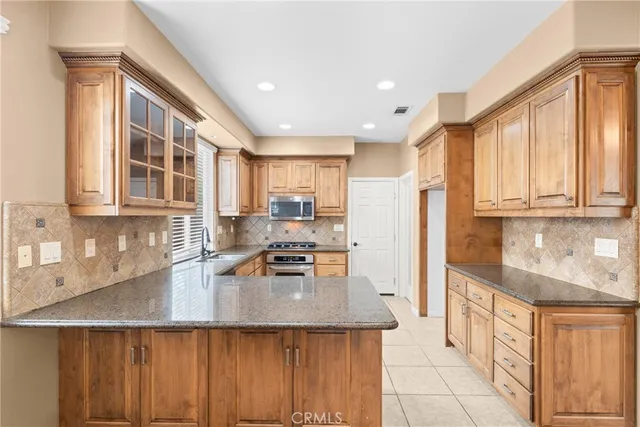 a kitchen with stainless steel appliances granite countertop a refrigerator a sink dishwasher a stove and white countertops with wooden floor