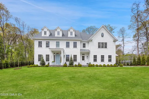 a front view of a house with a garden and trees