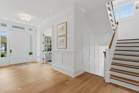 a view of an empty room with wooden floor and stairs