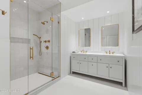 a spacious bathroom with double sink shower and two mirror