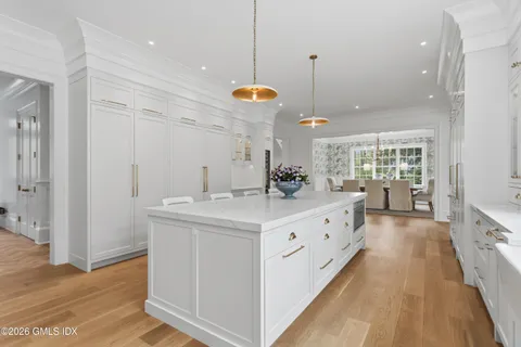 a large white kitchen with a large island oven a sink dishwasher and white cabinets with wooden floor