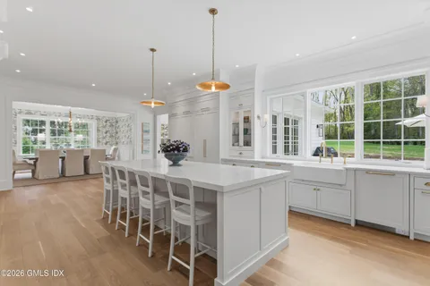 a kitchen with a dining table chairs and large windows
