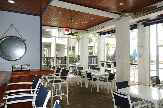 a room with lots of tables a large window and chairs