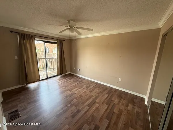 an empty room with wooden floor fan and windows