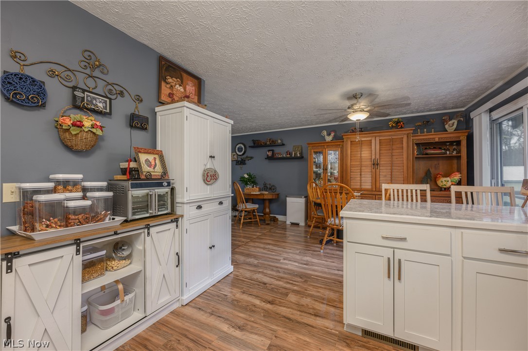 390 Ross Road Waynesburg, OH 44688 - Photo 6 of 30 Kitchen featuring a ceiling fan, white cabinetry, light wood-style floors, a textured ceiling, and a breakfast bar
