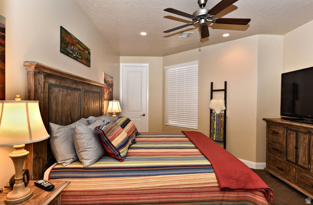 1622 Canyon Tree Drive St. George, UT 84770 - Photo 13 of 34 Interior room featuring a wood-finish headboard, textured beige walls, and a ceiling fan with integrated lighting