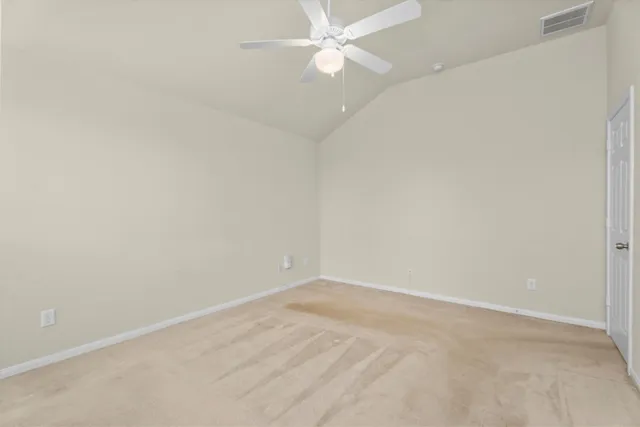 an empty room with a fan & a ceiling fan