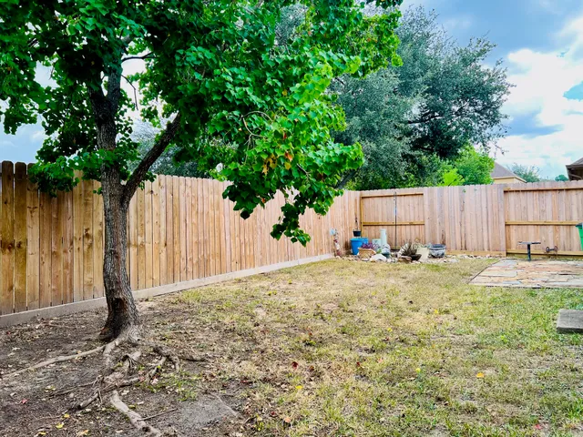a view of a backyard with wooden fence