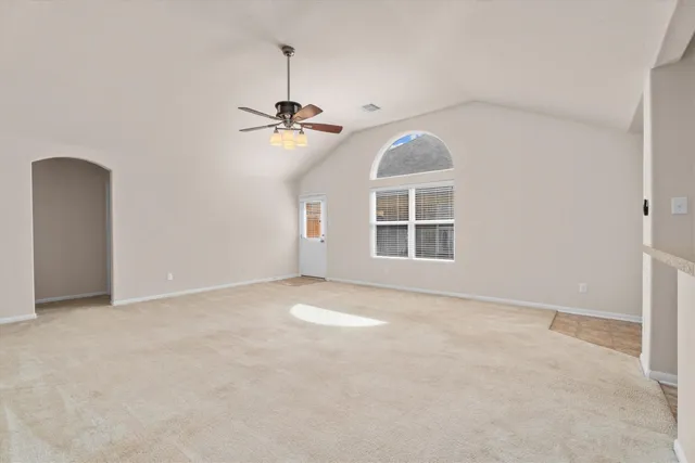 an empty room with a chandelier fan and windows