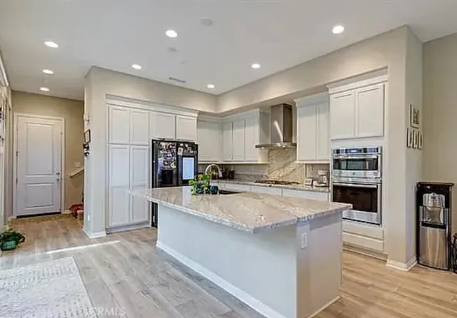a large kitchen with granite countertop a large counter top stainless steel appliances and cabinets