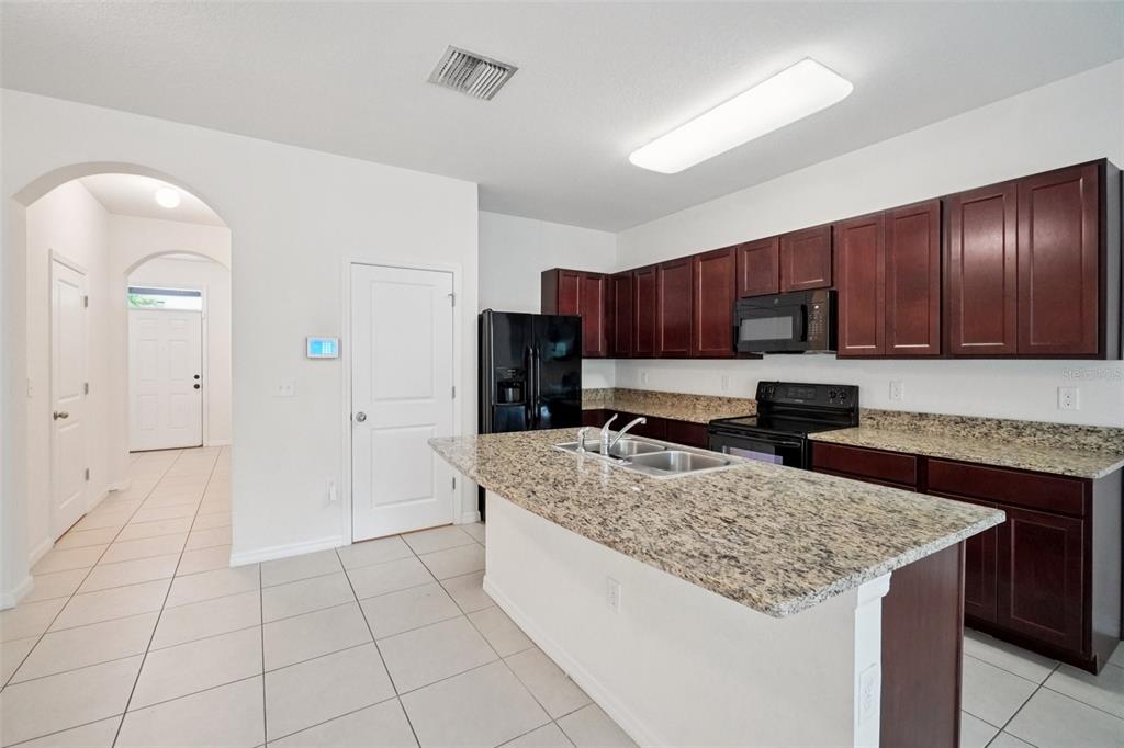 8986 Indigo Trail Loop Riverview, FL 33578 - Photo 18 of 48 a kitchen with kitchen island granite countertop a stove a sink and a refrigerator