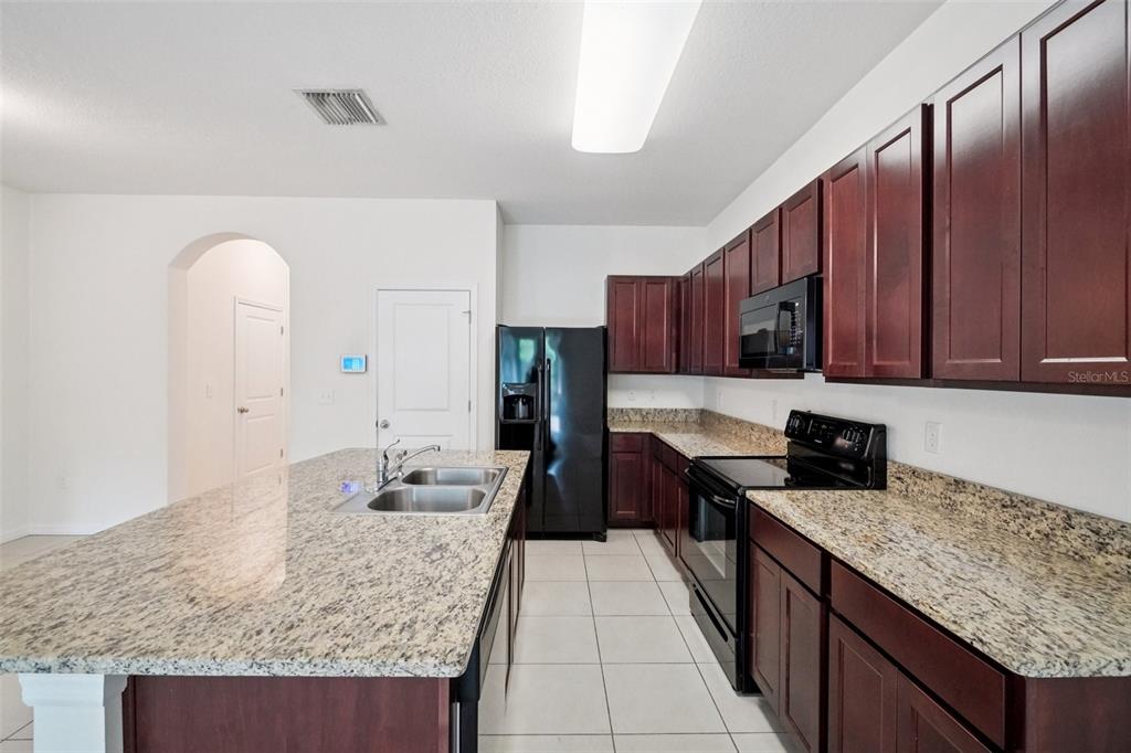 8986 Indigo Trail Loop Riverview, FL 33578 - Photo 20 of 48 a kitchen with granite countertop a sink dishwasher stove and cabinets