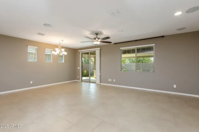 an empty room with windows and ceiling fan