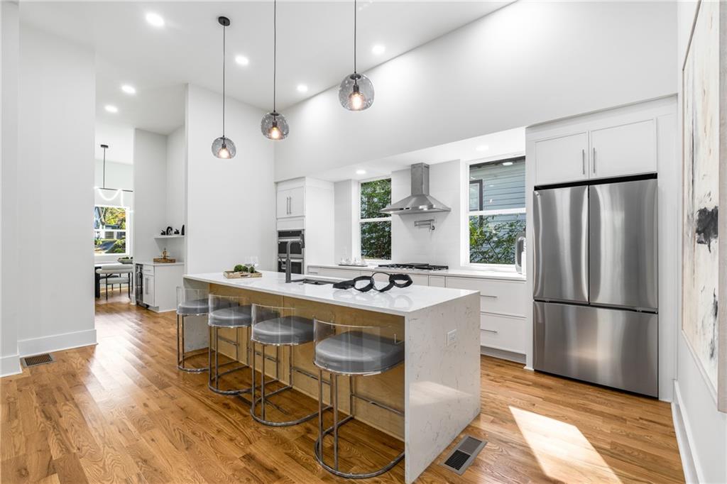271 Haas Avenue Southeast Atlanta, GA 30316 - Photo 9 of 56 a kitchen with kitchen island a refrigerator a stove a dining table and chairs with wooden floor