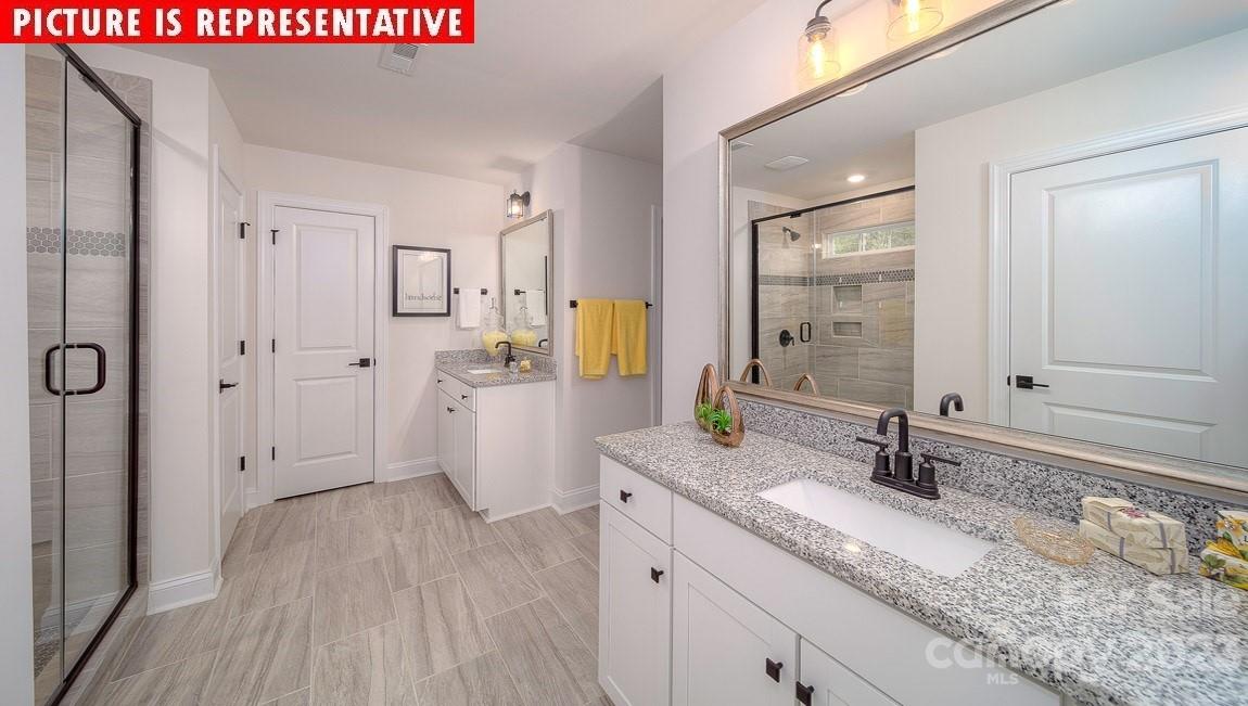 309 Streamwood Road Troutman, NC 28166 - Photo 16 of 47 a bathroom with a granite countertop sink a mirror a vanity and a shower