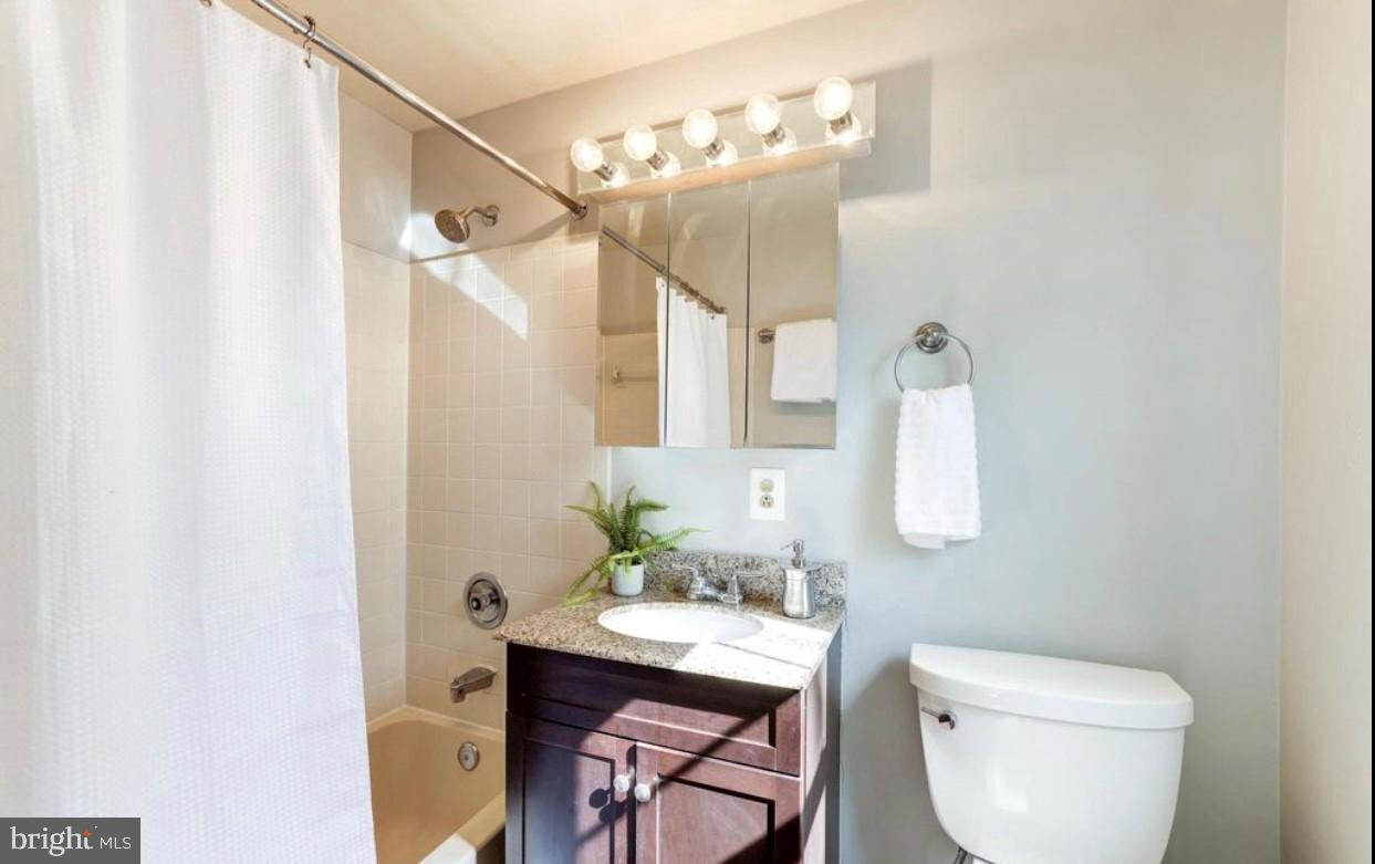 1742 North Rhodes Street, Unit 5304 Arlington, VA 22201 - Photo 10 of 11 a bathroom with a granite countertop sink a toilet and a mirror