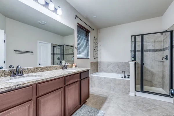 a bathroom with a granite countertop bathtub shower sink vanity and mirror