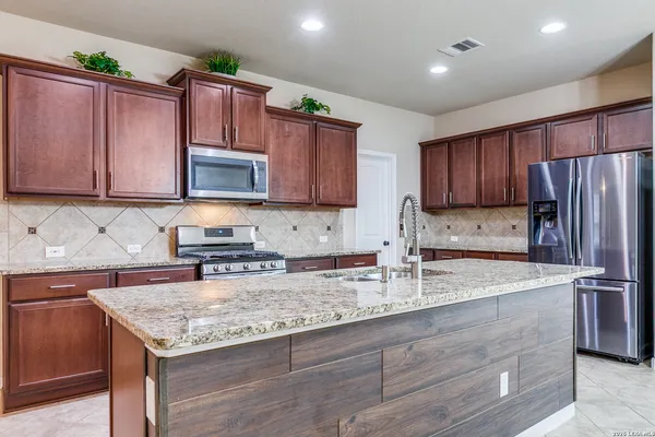 a kitchen with granite countertop a sink stove and refrigerator