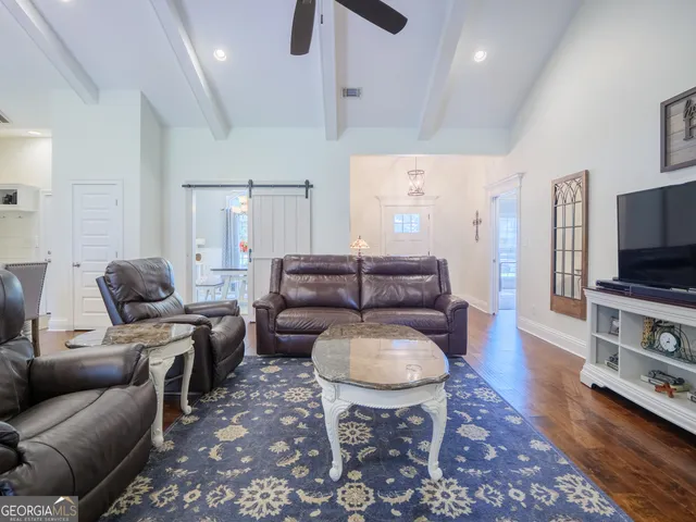a living room with furniture a large window and wooden floor