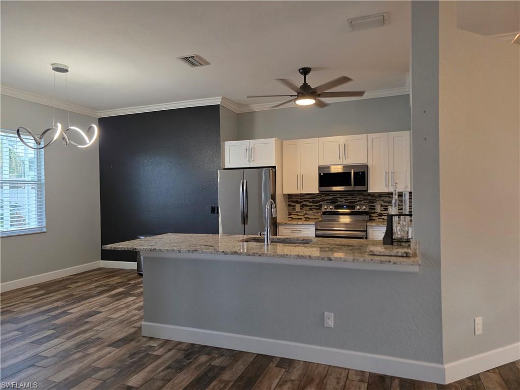 857 Summerfield Drive Naples, FL 34120 - Photo 12 of 50 a kitchen with stainless steel appliances granite countertop a refrigerator a sink dishwasher a stove and white countertops with wooden floor