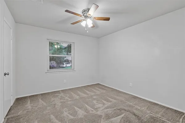 an empty room with a chandelier fan and windows