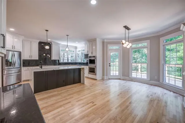 a large kitchen with kitchen island a sink dishwasher a refrigerator and wooden floor