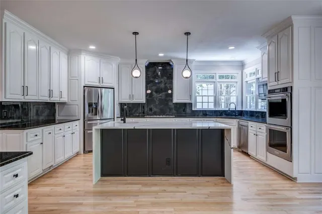 a large kitchen with stainless steel appliances kitchen island granite countertop a stove a refrigerator and a wooden cabinets