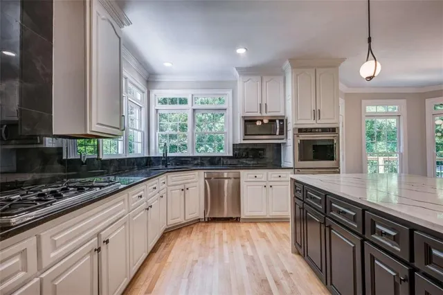 a kitchen with stainless steel appliances kitchen island granite countertop a stove sink and cabinets