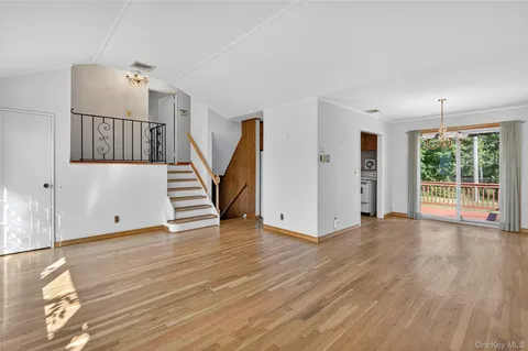 a view of an empty room with wooden floor and windows