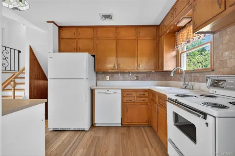 a kitchen with a white cabinets sink and wooden floor