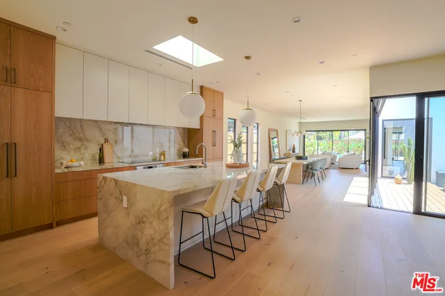 a large kitchen with kitchen island a large counter top space a sink stainless steel appliances and cabinets