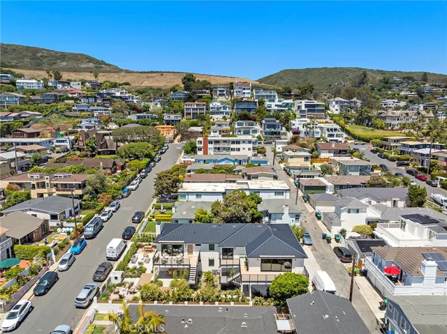 an aerial view of ocean and residential houses with outdoor space