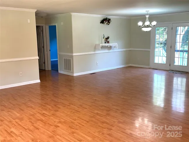a view of an empty room with window and wooden floor