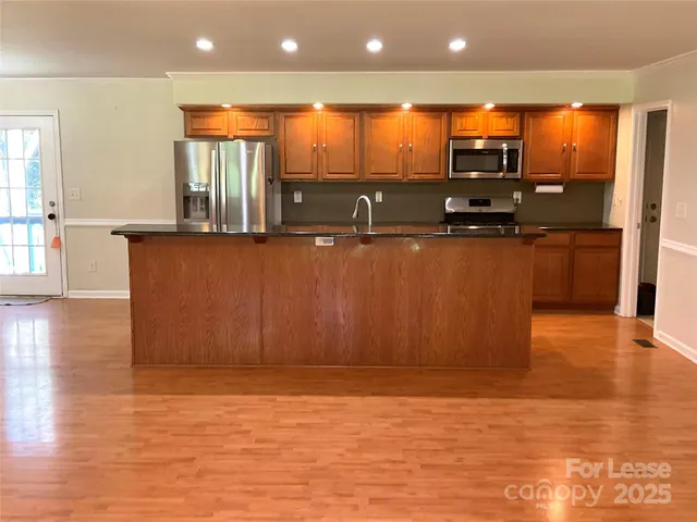 a view of kitchen island with stainless steel appliances wooden floor and window