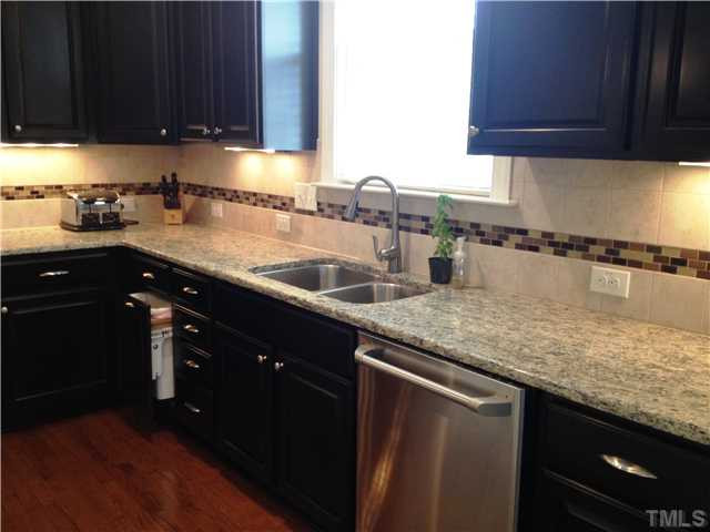 3614 Silver Forrest Lane Raleigh, NC 27614 - Photo 7 of 25 The kitchen has a designer tile backsplash and under cabinet lighting. A pull out trash and recycling center is housed in one of the lower cabinets. Kitchen