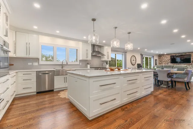 a kitchen with stainless steel appliances kitchen island granite countertop a stove a sink and white cabinets