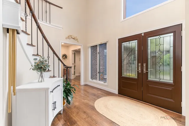 a view of an entryway with wooden floor leading to a furnished livingroom and windows