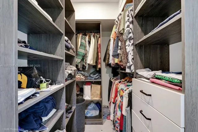 a view of walk in closet with clothes and shoes