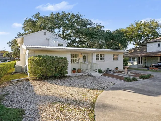 a view of a house with a yard plants and large tree
