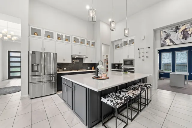 a kitchen with stainless steel appliances a sink a stove a refrigerator and chairs