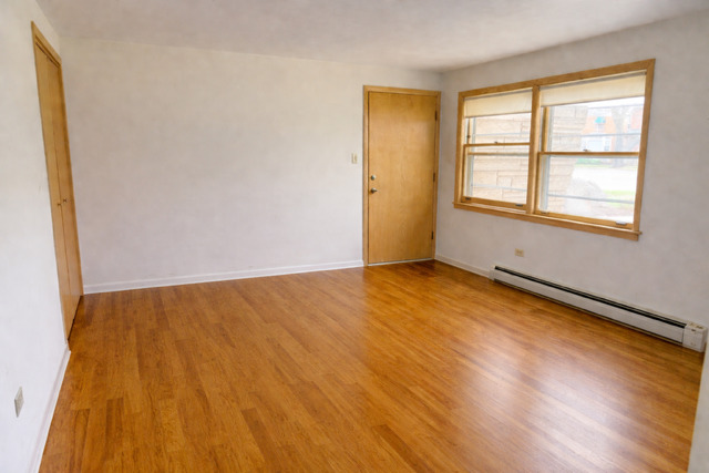8304 W Forest, Unit 3W Chicago, IL 60634 - Photo 2 of 8 a view of an empty room with wooden floor and a window