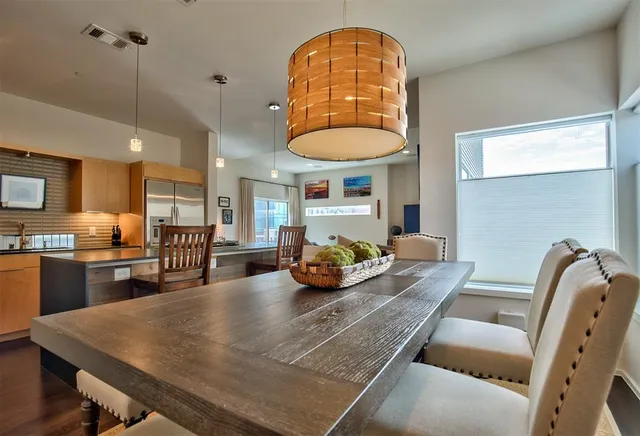 a room with stainless steel appliances furniture dining table and kitchen view