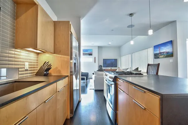 a kitchen with stainless steel appliances granite countertop a sink a stove and a refrigerator