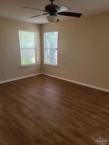 an empty room with wooden floor chandelier fan and windows