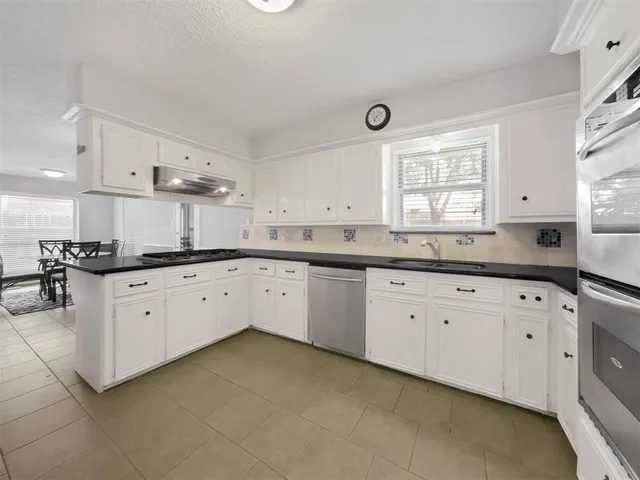 a kitchen with granite countertop white cabinets white stainless steel appliances with a sink and dishwasher