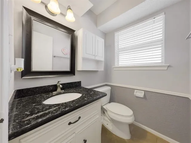 a bathroom with a granite countertop toilet sink and mirror