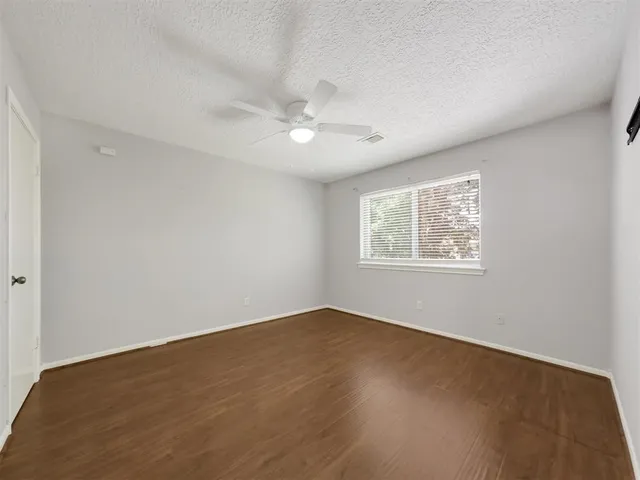 an empty room with a window and ceiling fan