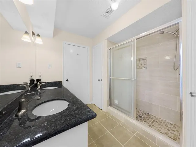 a bathroom with a granite countertop sink a mirror and shower