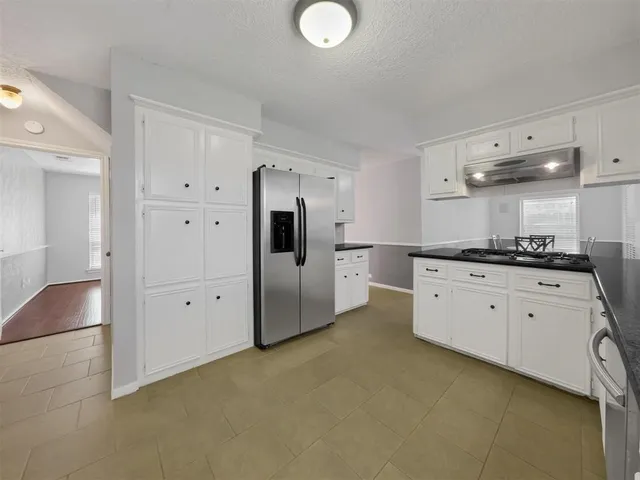 a kitchen with granite countertop white cabinets and white appliances